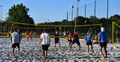 Terrain de sport de sable avec des personnes en train de jouer au beach volley